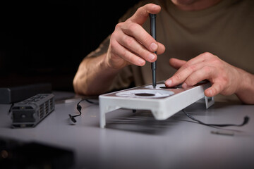 A technician is skillfully repairing a computer GPU fan with precision tools in a workshop