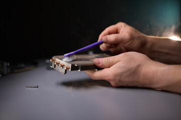 A technician is skillfully repairing a computer GPU fan with precision tools in a workshop