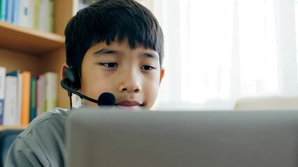 Teenage boy kid wearing a headset using laptop computer