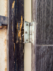 A wooden door jamb, so gnawed by termites that the hinges with screws no longer hold