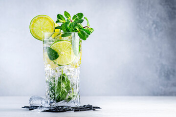 Caipirinha alcoholic cocktail drink with brazilian cachaca vodka, sugar syrup, lime, mint and crushed ice in highball glass on gray background