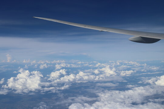 Aerial View of Urban Landscape with Airplane Wing Under Clear Blue Sky and Scattered Clouds