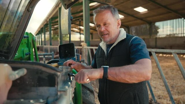 Close up of mature male farm worker with tool kit fixing machinery - shot in slow motion