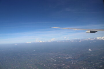 Aerial View of Urban Landscape with Airplane Wing Under Clear Blue Sky and Scattered Clouds