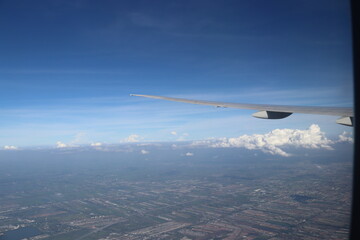 Aerial View of Urban Landscape with Airplane Wing Under Clear Blue Sky and Scattered Clouds