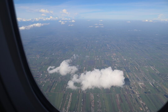 Aerial View of Urban Landscape with Airplane Wing Under Clear Blue Sky and Scattered Clouds