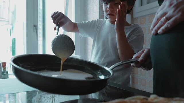 Child pouring pancake batter into a pan under supervision, kitchen background, focused expression, making breakfast, learning to cook, natural light