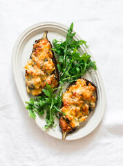 Stuffed with chicken, spinach, tomatoes and mozzarella cheese eggplant and arugula salad on an oval plate on a light surface