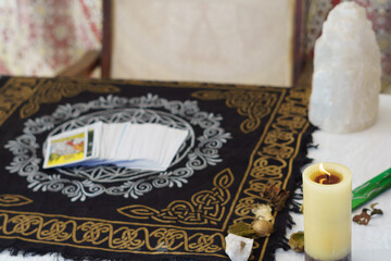 table of a fortune teller with tarot cards, candles, quartz stones, crystal ball on a white...