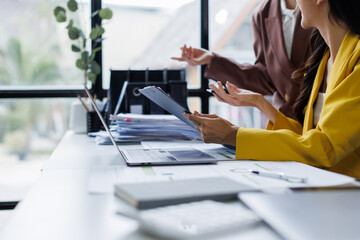 Analyst team colleague discuss financial data on digital dashboard, analyzing charts graph display on laptop and tablet screen. office use asian business intelligence to plan marketing. Enthusiastic
