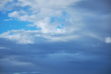 Obraz premium Sunset sky in bright blue tones. A wide panorama of the evening sky covered with dark clouds.