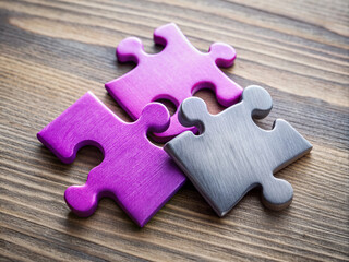 Fototapeta premium Three vibrant puzzle pieces in purple, pink, and grey hues sit perfectly aligned on a clean desk, symbolizing harmony and cohesion in creative problem-solving.