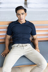 Handsome and good looking single gym fit and muscled male model with a black fashionable hairstyle and dark eyes, wearing a navy blue knitted polo and looking in the camera