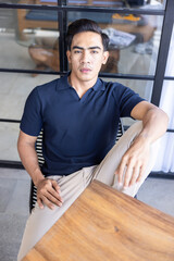 Handsome and good looking single gym fit and muscled male model with a black fashionable hairstyle and dark eyes, wearing a navy blue knitted polo