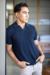 Handsome and good looking single gym fit and muscled male model with a black fashionable hairstyle and dark eyes, wearing a navy blue knitted polo