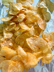 Lots of chips. Potato chips on foil. Junk food is chips.