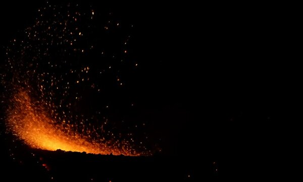 Fiery glowing sparks from a fire set against a black background, captured in slow motion to emphasize the intensity and movement of the sparks
