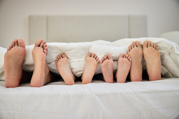 People, sleeping and feet in bed with blanket for peace, comfort and support in house as bonding....