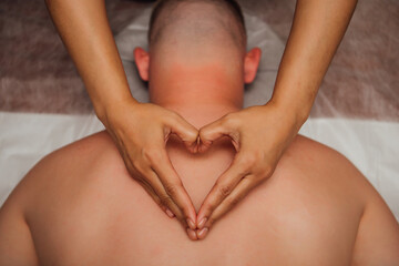Masseur's hands in the shape of a heart on the man's back