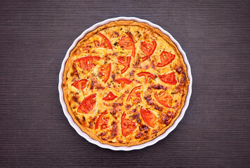 Delicious homemade quiche with fresh tomato slices and melted cheese, baked to perfection in a ceramic dish. A perfect savory pie for breakfast, brunch, or dinner.