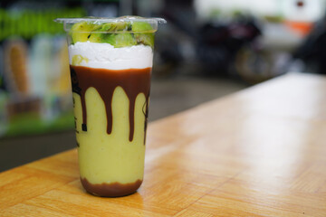 Avocado juice Smoothie in a glass served with sweet chocolate condensed milk
