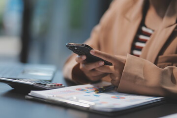 Fototapeta premium Young beautiful Asian businesswoman holding smartphone while working in the office room.