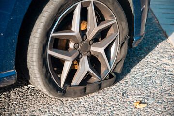 Flat Tire on Blue Car Parked on Gravel Road