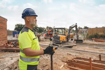 Construction Worker Using Surveying Equipment on Construction Site