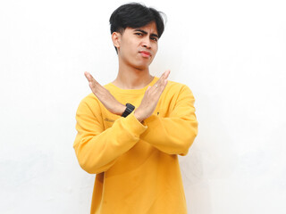 Portrait of an Asian young adult man wearing a yellow sweater, showing an angry expression and...