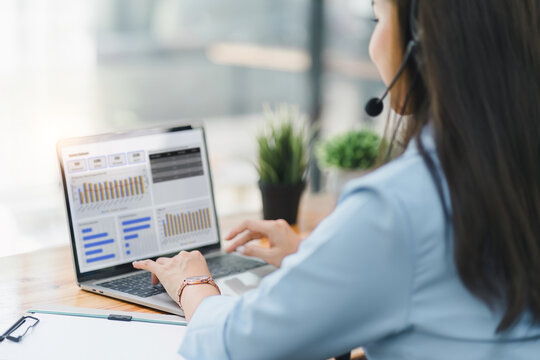 Operator wearing a headset, using a dashboard on laptop for data analysis in modern office. Selective focus