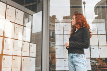 Woman Reading Job Listings On Glass Board In City