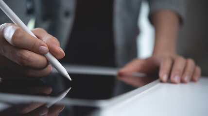 Close up, woman hand using stylus pen on digital tablet on office table. Graphic designer working...