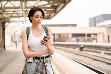 Woman Checking Phone at Train Station Platform