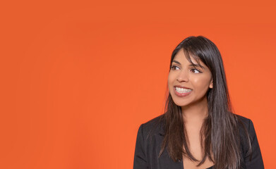 Obraz premium Smiling Indian Woman Looking Off Camera Against Orange Background