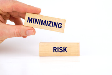 MINIMIZING RISK word written on wooden blocks with a man's hand on a white background