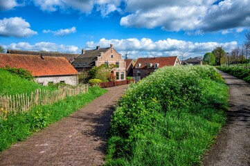 Fototapeta premium A village scene with traditional brick houses, lush greenery, and a clear blue sky.