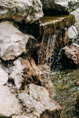 Artificial waterfall of stones and flowers in a landscaped green garden