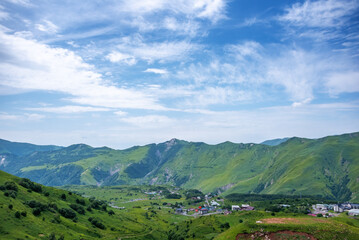 Fototapeta premium View of Gudauri in summer. A beautiful village, a modern center of Georgian tourism and a ski resort, located on the southern slopes of the Greater Caucasus Range