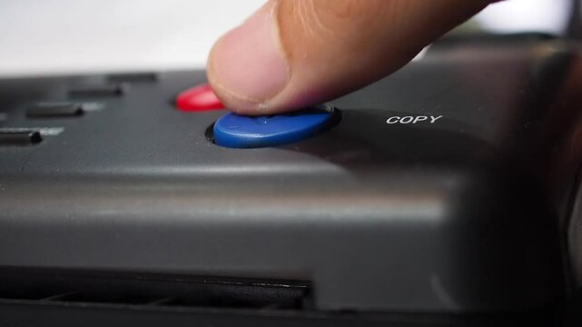 Close up shot putting paper to scanner and then finger pushing copy blue button on stencil copy machine to make a copy