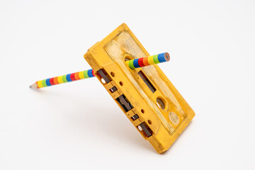 Old music magnetic cassette and wooden pencil on white background