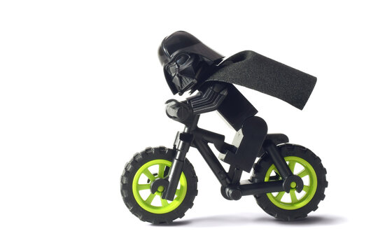 Lego minifigure of Darth Vader or Star Wars male is riding a bike isolated on white. Editorial illustrative image of popular plastic constructor and 25 Anniversary.