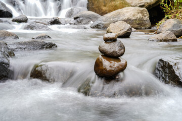 A Closeup of stacked rocks, Stack of zen stones in the background of a flowing river