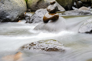 A Closeup of stacked rocks, Stack of zen stones in the background of a flowing river