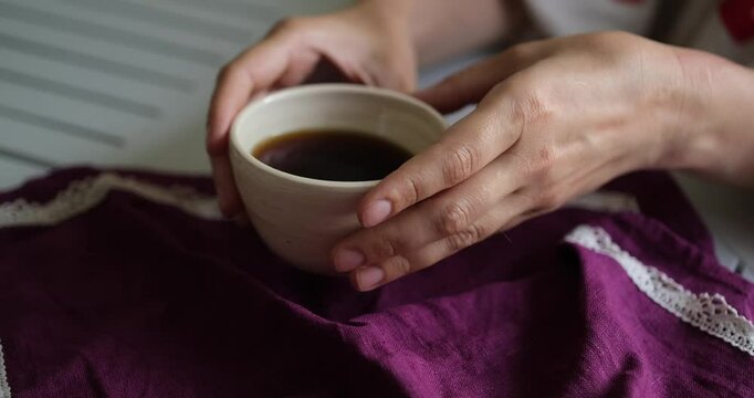 Female hand on the white table with ceramic cup of coffee. Rest relax concept. Vintage village mood. Close up. video footage 4k