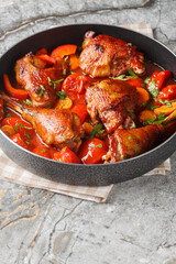 Homemade rooster cooked with vegetables in tomato sauce close-up in a pan on the table. Vertical