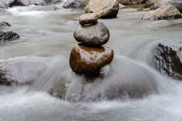 A Closeup of stacked rocks, Stack of zen stones in the background of a flowing river