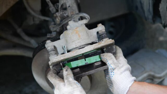 Mechanic man installing new brake disc and brake pads on car, car repair