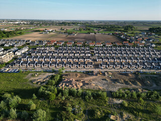 Rows of identical new, single-family houses in a suburban estate, real estate market, modern suburban housing track, aerial view.