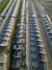 Rows of identical new, single-family houses in a suburban estate, real estate market, modern suburban housing track, aerial view.