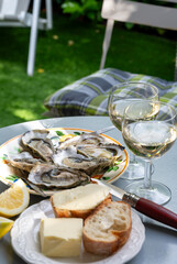Plate with fresh live oysters with citron, bread, butter and white wine served at restaurant in...